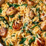 Creamy chicken sausage orzo skillet garnished with fresh parsley and lemon zest in a large pan