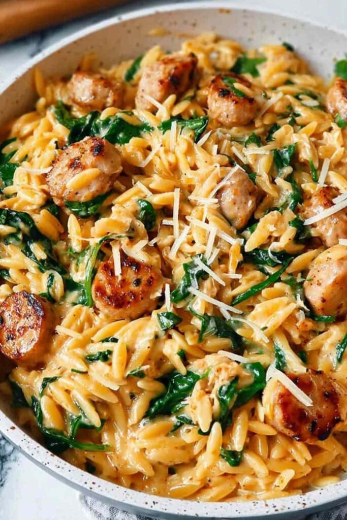 Creamy chicken sausage orzo skillet garnished with fresh parsley and lemon zest in a large pan