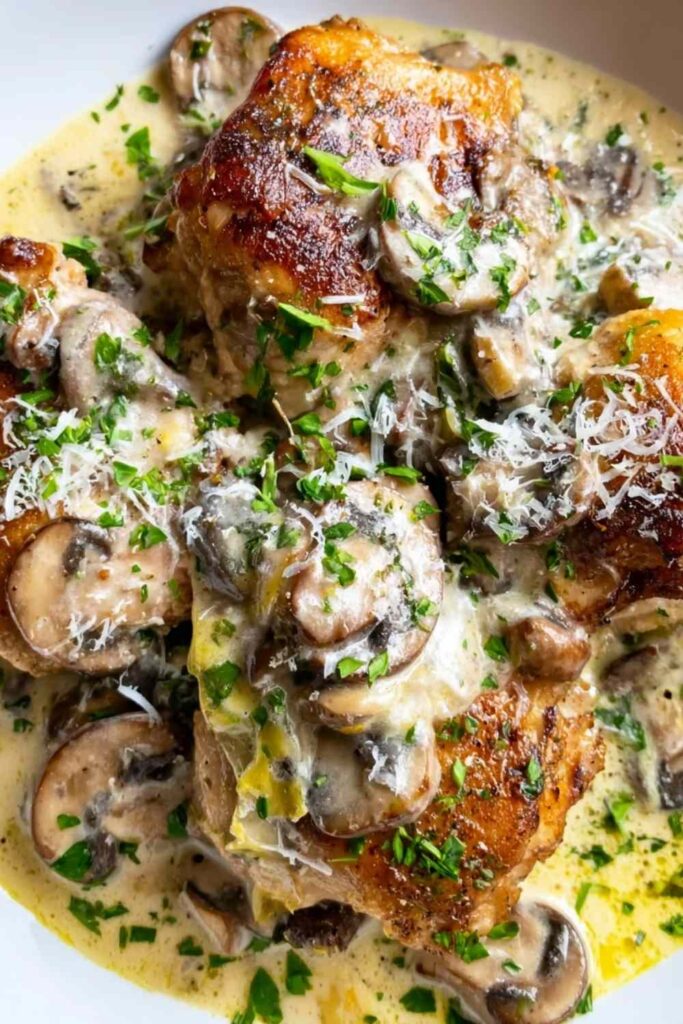 Creamy garlic Mushroom Chicken Thighs 6 Creamy garlic mushroom chicken thighs in a cast iron skillet with golden crispy skin and rich garlic mushroom sauce