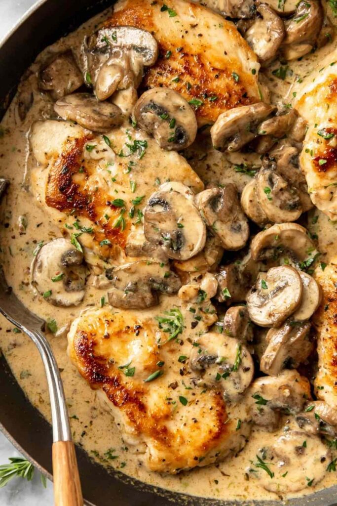Creamy mushroom chicken in skillet with golden chicken and rich garlic sauce