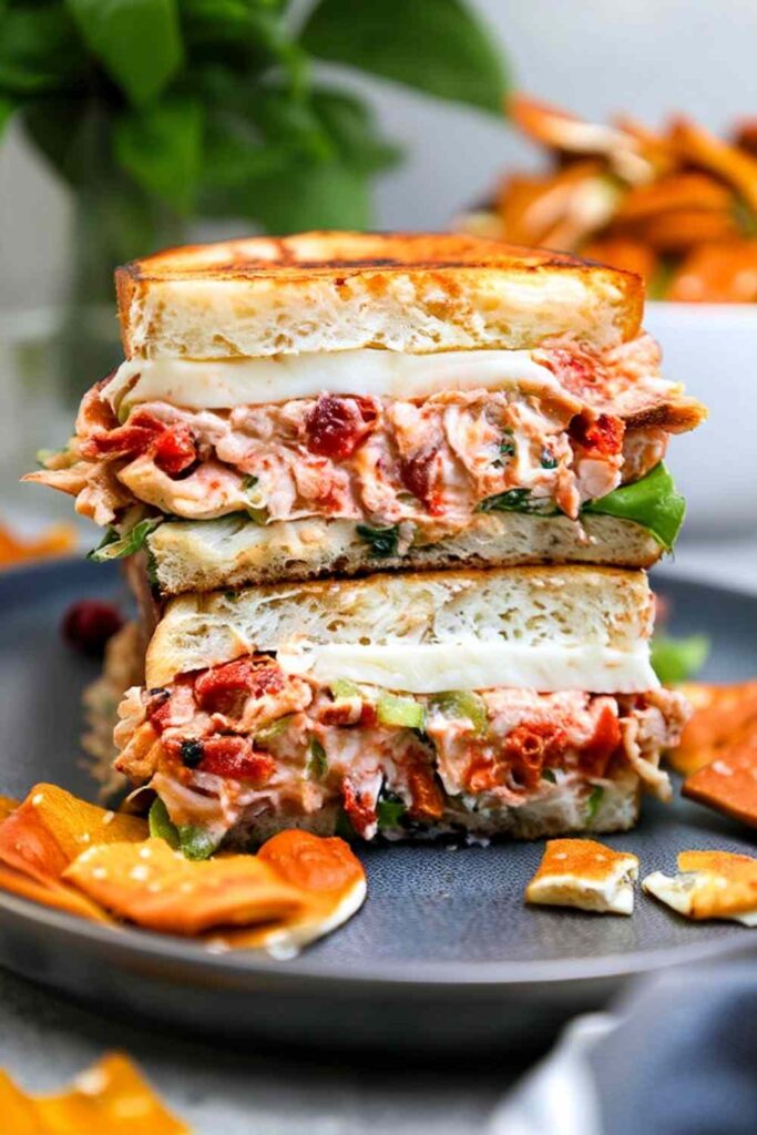 Sun-dried tomato chicken salad in a white bowl with fresh basil garnish