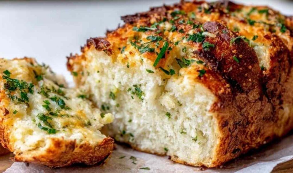 Crispy garlic Parmesan bread on a baking sheet with golden melted cheese and fresh chopped parsley