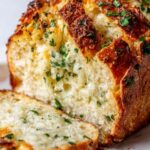 Crispy garlic Parmesan bread on a baking sheet with golden melted cheese and fresh chopped parsley