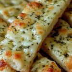 Crispy sourdough cheesy breadsticks on parchment paper with golden melted cheese