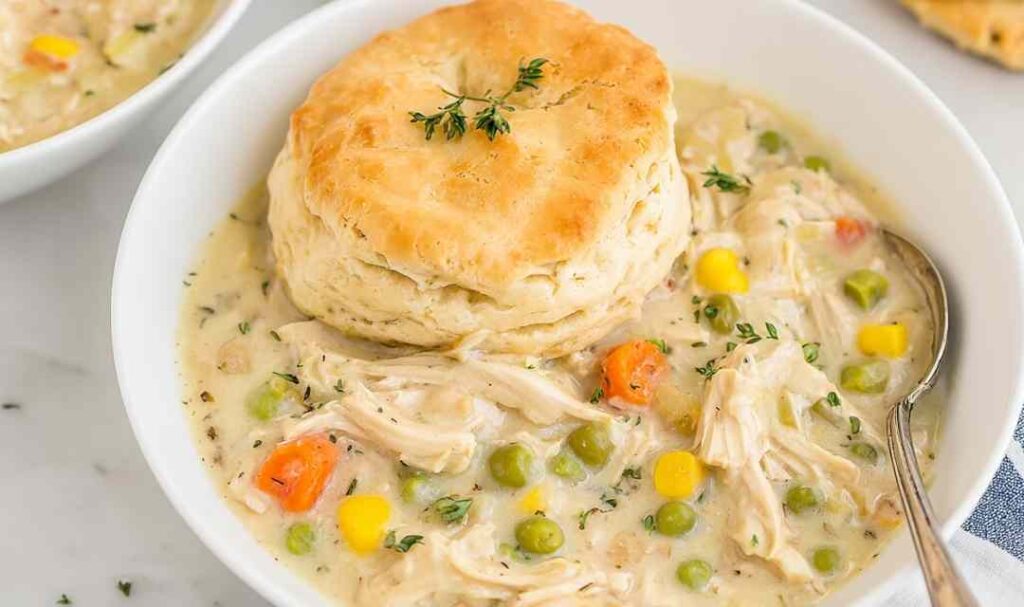 Crockpot chicken pot pie with golden biscuits on top in slow cooker
