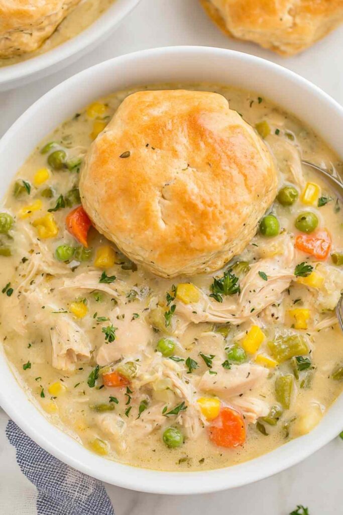 Crockpot chicken pot pie with golden biscuits on top in slow cooker