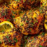 Crockpot lemon garlic chicken thighs on a white serving platter drizzled with buttery lemon garlic sauce and garnished with fresh parsley