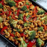 Sheet pan cashew chicken with broccoli bell peppers and cashews on a baking sheet