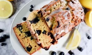 Sliced sourdough discard lemon blueberry quick bread with white glaze and fresh blueberries