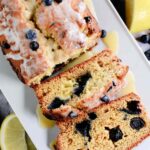 Sliced sourdough discard lemon blueberry quick bread with white glaze and fresh blueberries