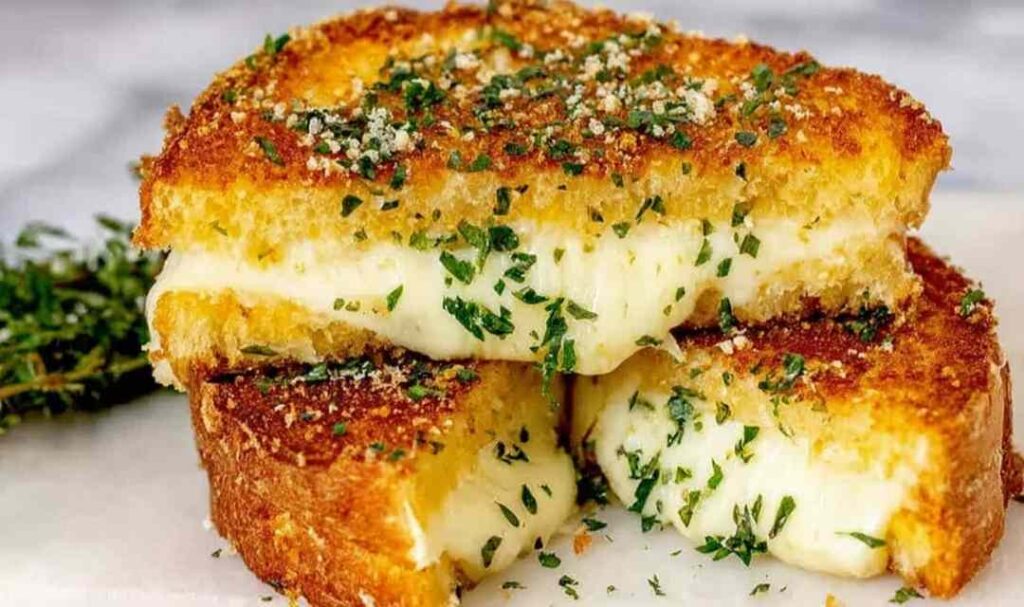 Garlic Bread Grilled Cheese 5 Garlic bread grilled cheese sandwich cut diagonally showing melted cheese pull on a wooden board