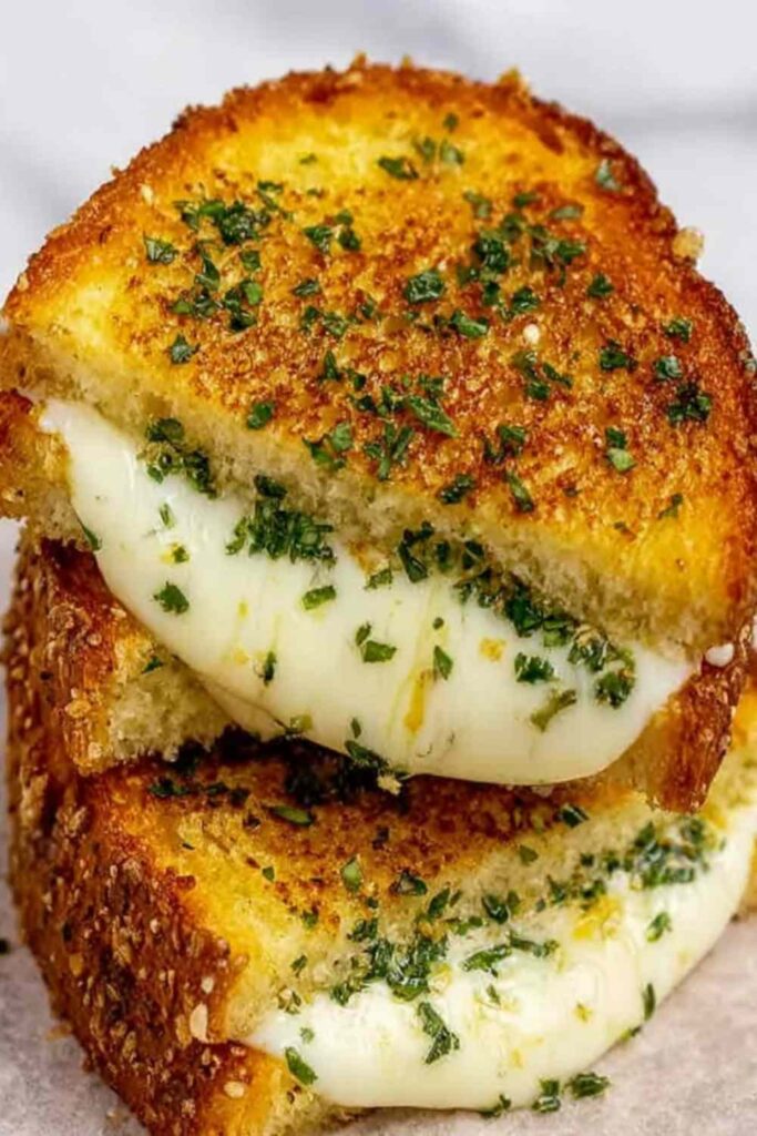 Garlic Bread Grilled Cheese 6 Garlic bread grilled cheese sandwich cut diagonally showing melted cheese pull on a wooden board