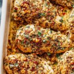 Garlic parmesan chicken bake on white plate with golden crispy crust and fresh parsley garnish