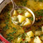 Creamy garlic potato soup in white bowl garnished with fresh parsley and croutons