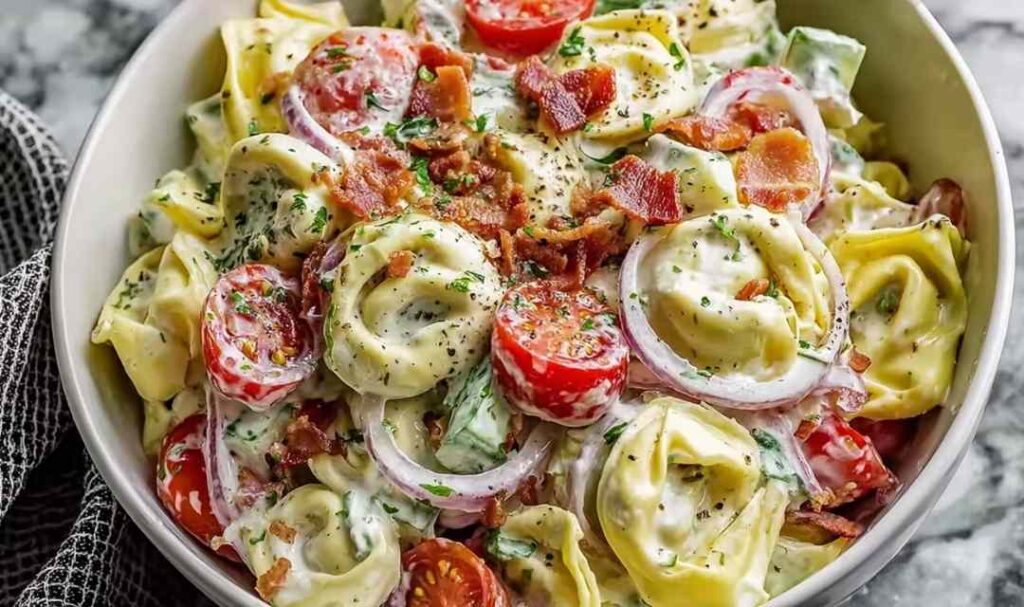 Fresh grinder tortellini salad with salami, pepperoni, provolone, cherry tomatoes, and zesty Italian dressing in a large white bowl