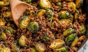 Ground beef and brussels sprouts in skillet with sweet chili sauce and sesame seeds