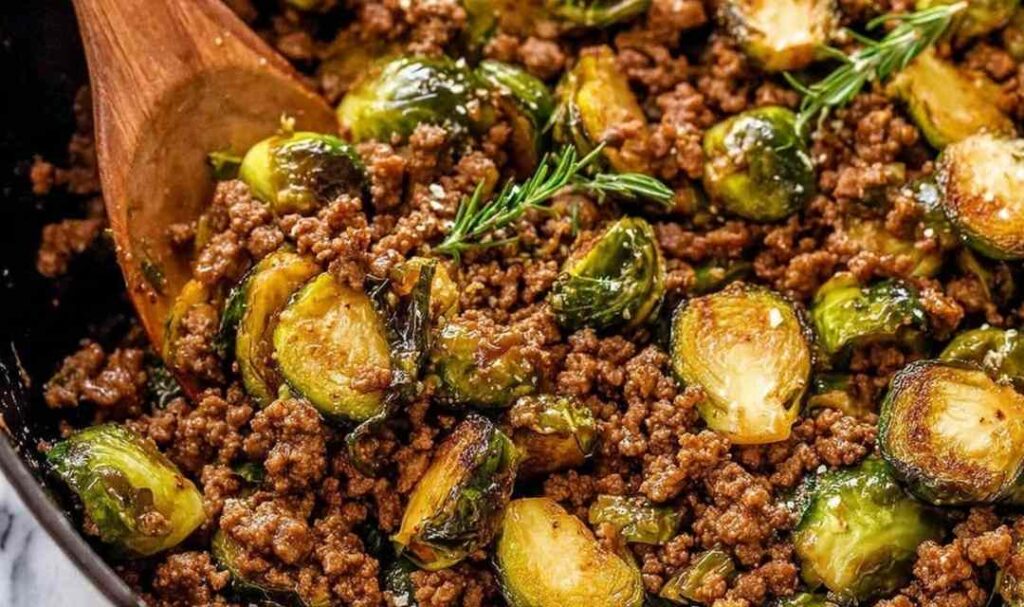 Ground beef and brussels sprouts in skillet with sweet chili sauce and sesame seeds