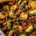 Ground beef and brussels sprouts in skillet with sweet chili sauce and sesame seeds