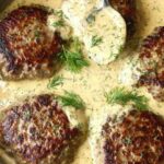 Hamburger steak in creamy dill sauce served over mashed potatoes in a cast iron skillet