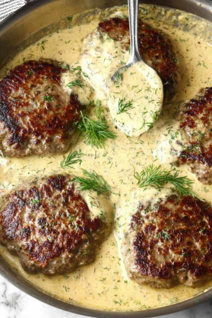 Hamburger Steak in Creamy Dill Sauce 6 Hamburger steak in creamy dill sauce served over mashed potatoes in a cast iron skillet