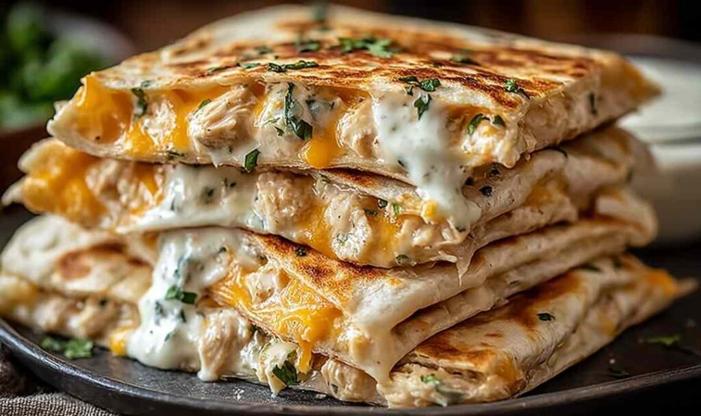 High protein chicken ranch quesadilla cut into wedges on white plate with sour cream and salsa