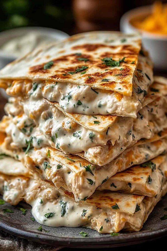 High protein chicken ranch quesadilla cut into wedges on white plate with sour cream and salsa