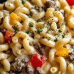 High protein Philly cheesesteak mac and cheese in a skillet with melted provolone and fresh parsley