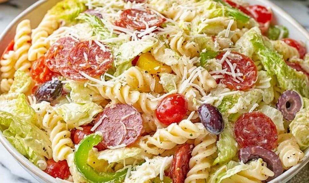 Italian grinder pasta salad with rotini, pepperoni, ham, provolone, and banana peppers in a white bowl