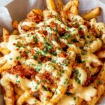 Louisiana Voodoo Fries topped with creamy cheese sauce, ranch drizzle, and Cajun seasoning on a serving platter