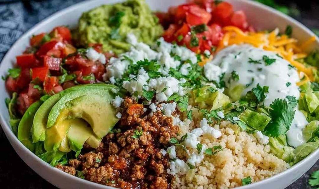Low carb burrito bowl with seasoned chicken, cauliflower rice, black beans, corn, cheese, and pico de gallo