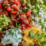Low carb burrito bowl with seasoned chicken, cauliflower rice, black beans, corn, cheese, and pico de gallo