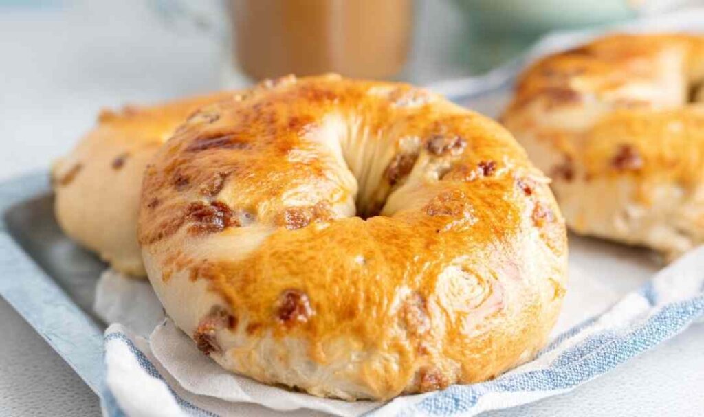 Golden brown maple french toast bagel on white plate with maple syrup drizzle