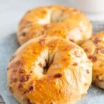 Golden brown maple french toast bagel on white plate with maple syrup drizzle