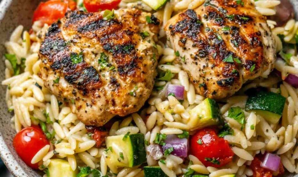 Mediterranean chicken orzo in a Dutch oven topped with crumbled feta, kalamata olives, and fresh parsley