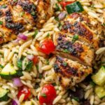 Mediterranean chicken orzo in a Dutch oven topped with crumbled feta, kalamata olives, and fresh parsley