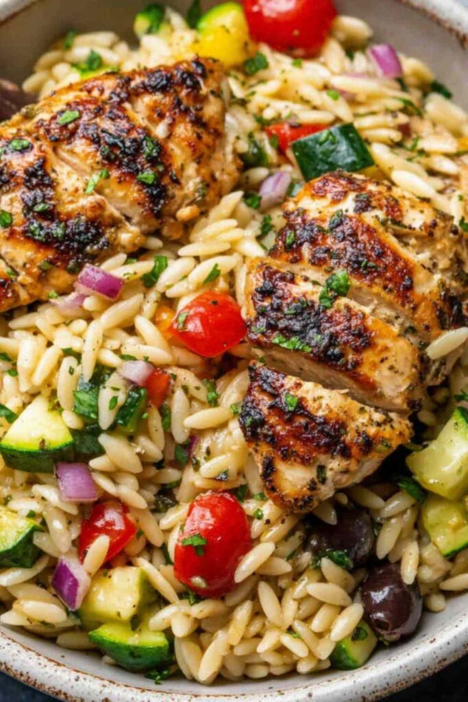 Mediterranean chicken orzo in a Dutch oven topped with crumbled feta, kalamata olives, and fresh parsley