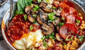 Pizza protein bowl with shredded chicken, quinoa, melted mozzarella, bell peppers, and pizza sauce in a white bowl