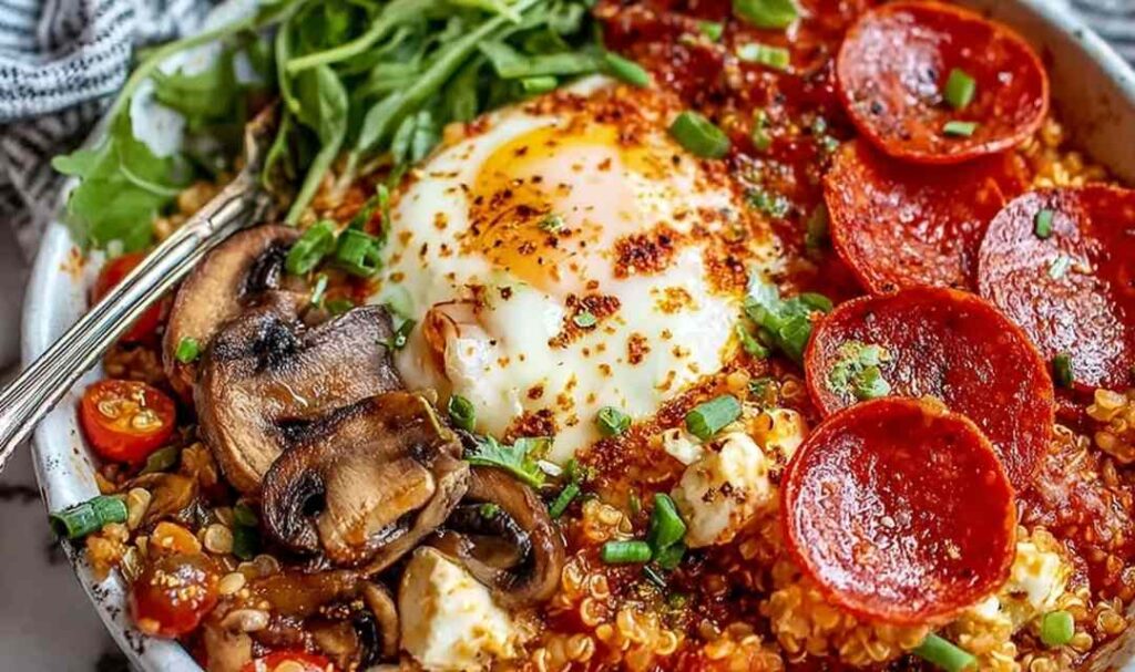 Pizza Protein Bowl 5 Pizza protein bowl with shredded chicken, quinoa, melted mozzarella, bell peppers, and pizza sauce in a white bowl