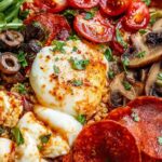 Pizza protein bowl with shredded chicken, quinoa, melted mozzarella, bell peppers, and pizza sauce in a white bowl
