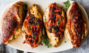 Roasted Bone-In Chicken Breasts Golden roasted bone-in chicken breasts with crispy skin on white plate with roasted vegetables