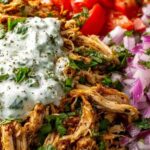 Slow cooker chicken shawarma wrap with tahini sauce, fresh tomatoes, cucumbers, and parsley on a wooden board