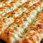 Sourdough cheesy breadsticks with melted cheese and garlic butter on baking sheet