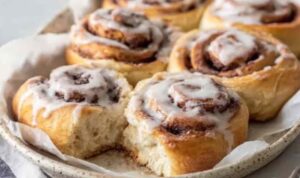 Freshly baked sourdough discard cinnamon rolls with white icing in a baking dish