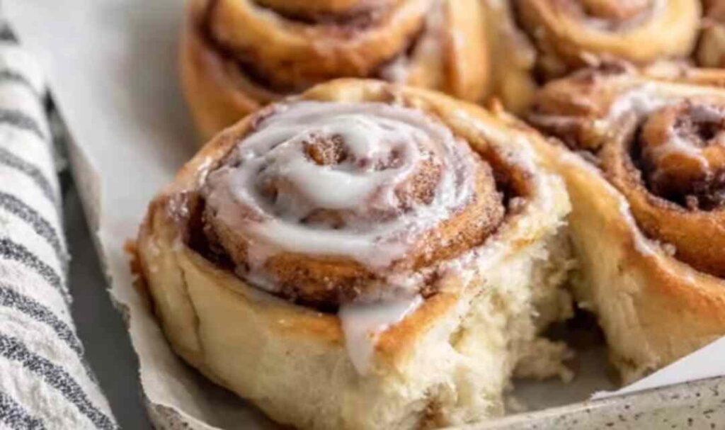 Freshly baked sourdough discard cinnamon rolls with white icing in a baking dish