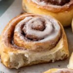 Freshly baked sourdough discard cinnamon rolls with white icing in a baking dish