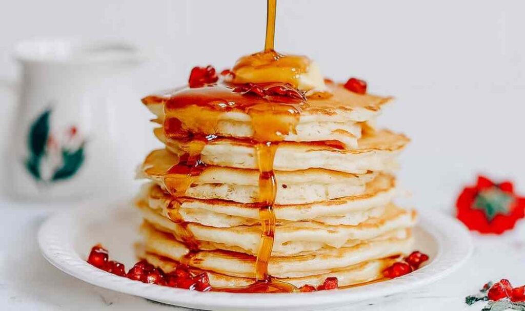 Stack of fluffy sourdough discard pancakes with butter and maple syrup dripping down the sides