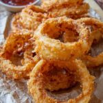 Golden crispy sourdough onion rings on white plate with dipping sauce