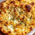 Cottage cheese flatbread on a baking sheet with golden brown edges and everything bagel seasoning on top