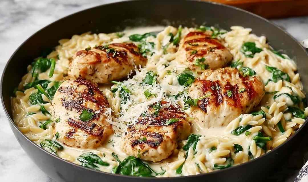 Boursin orzo with chicken in a skillet topped with fresh basil and Parmesan