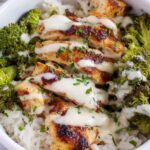 Chicken and broccoli bowls with creamy garlic sauce served over white rice with fresh parsley garnish